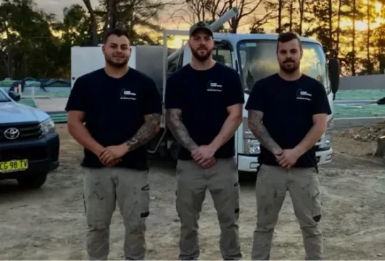 three plumbers smiling at looking at the camera